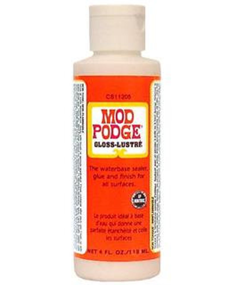 May include: A 4-ounce bottle of Mod Podge Gloss-Lustre, a water-based sealant, glue, and finish for all surfaces. The bottle is white with a light beige liquid inside. The label is orange with white text and a green logo.