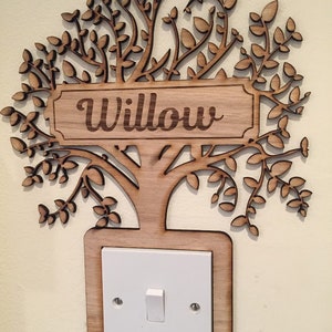 May include: A wooden tree cutout with a light switch plate behind it. The tree has a sign that says "Willow".
