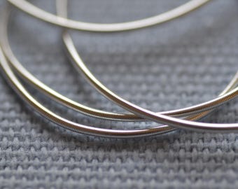 May include: Close-up of three silver metal rings, intertwined and overlapping, creating a circular pattern. The rings have a smooth, polished finish and a subtle sheen.