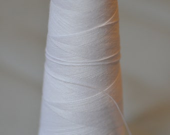 May include: A white spool of thread with a blue plastic top. The thread is wound tightly around the spool.