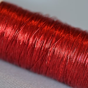 May include: A spool of shiny red metallic thread.