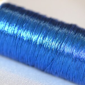 May include: A spool of metallic blue thread.