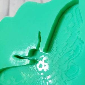 Op de afbeelding: Een groene siliconen mal van een nachtvlinder met een schedelontwerp. De mal is ontworpen om te worden gebruikt voor het maken van harsambachten.