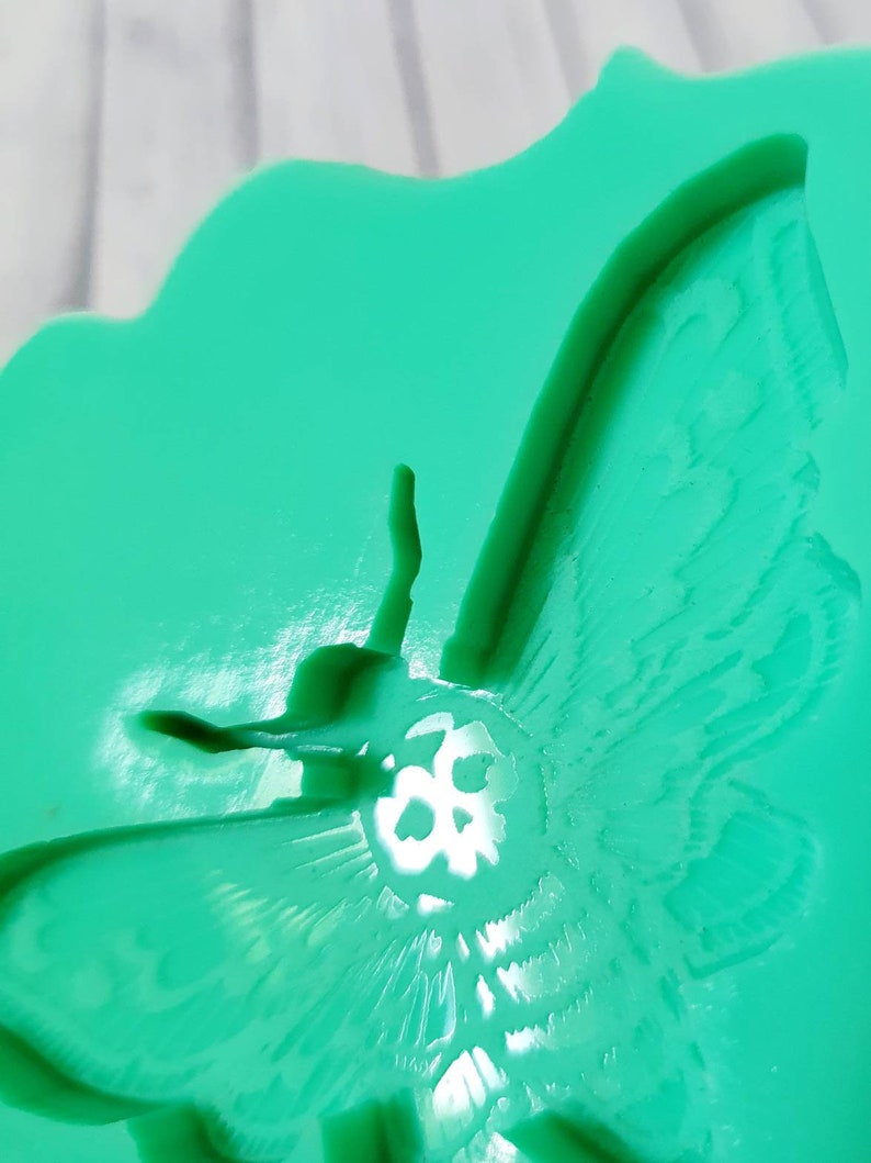 Op de afbeelding: Een groene siliconen mal van een nachtvlinder met een schedelontwerp. De mal is ontworpen om te worden gebruikt voor het maken van harsambachten.