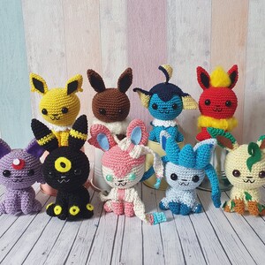 May include: A collection of eight crocheted Pokemon characters, including Pikachu, Eevee, and Charmander. The characters are all different colors and have different expressions on their faces.