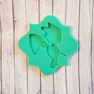 Puede incluir: Molde de silicona verde con un diseño de un personaje de dibujos animados sosteniendo una red. El personaje lleva un sombrero y tiene una nariz larga.