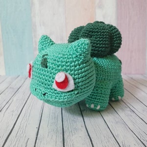 May include: Green crocheted stuffed toy resembling a turtle with a brown shell and white eyes.