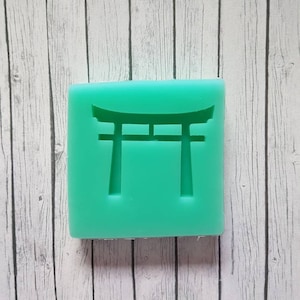 Könnte beinhalten: Eine grüne Silikonform mit einem erhabenen Design eines traditionellen japanischen Torii-Tores.