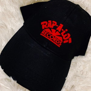 Könnte beinhalten: Schwarze Baseballkappe mit rotem "Rap-A-Lot Records" Logo.