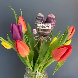 Könnte beinhalten: Ein Strauß Tulpen in einer durchsichtigen Glasvase mit einem herzförmigen Filz-Anhänger, auf dem "Granny" steht.