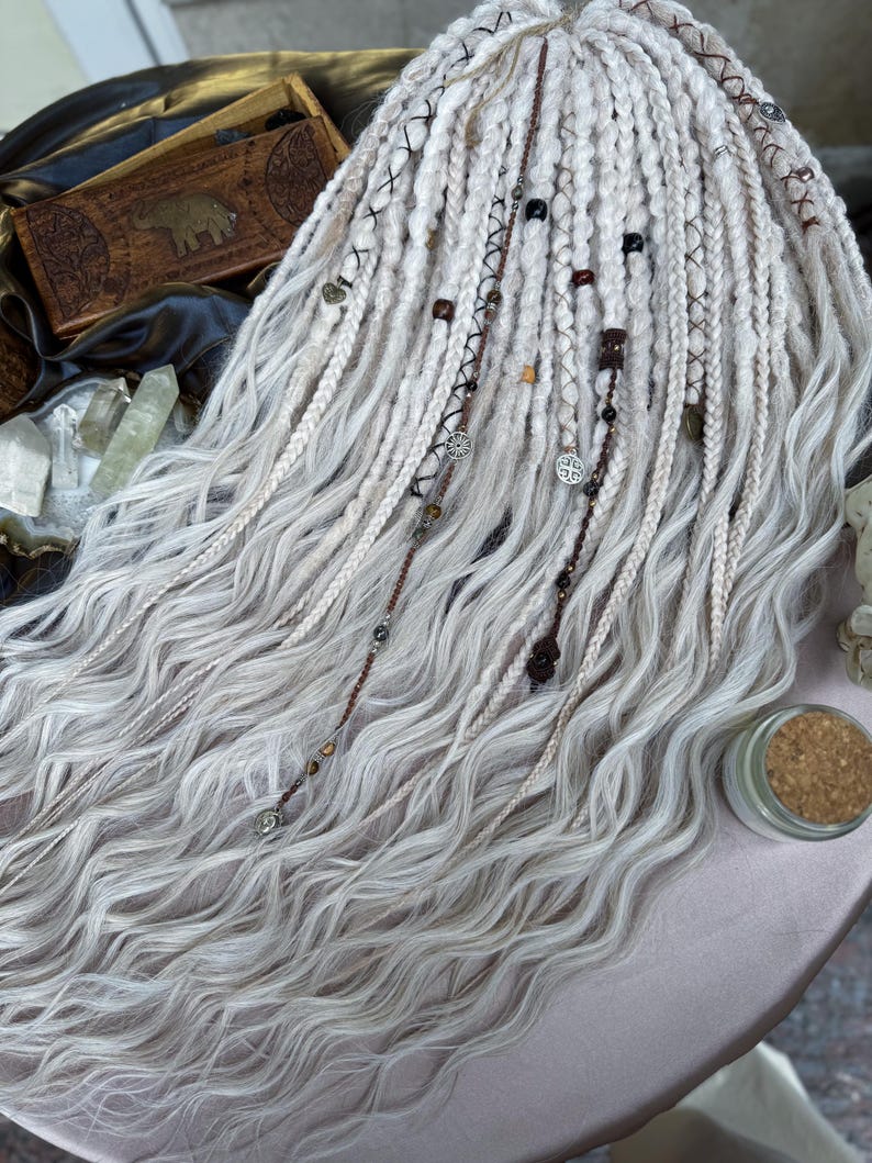 May include: White synthetic dreadlocks with wavy texture, adorned with brown leather cord, beads, and metal charms.
