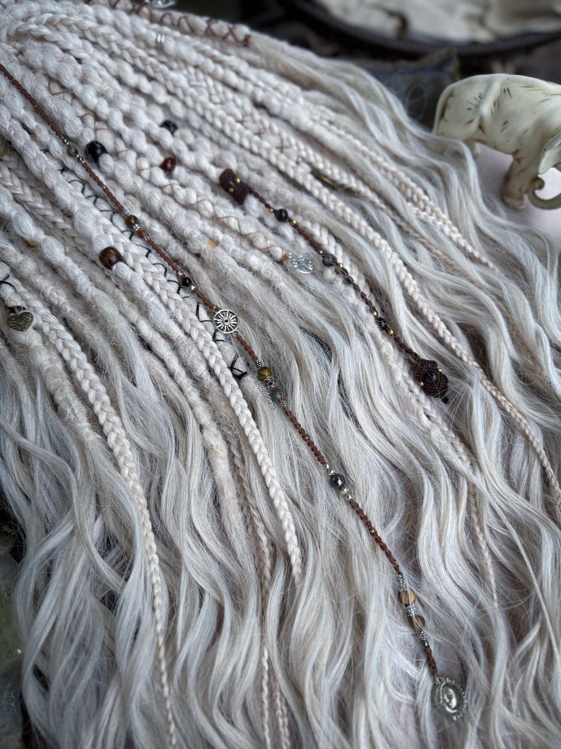 May include: White and brown synthetic dreadlocks with beads and charms. The dreadlocks are long and wavy.