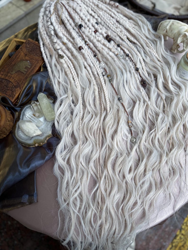 May include: White synthetic dreadlocks with brown and silver beads. The dreadlocks are wavy and have a natural look.