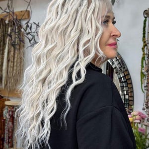 Puede incluir: Una mujer con el pelo largo, blanco y ondulado, peinado en rastas. Lleva un jersey negro.