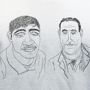 Può includere: T-shirt bianco con un disegno a tratto nero di due uomini. Uno ha i baffi, l'altro una giacca. L'illustrazione è centrata sulla maglietta.