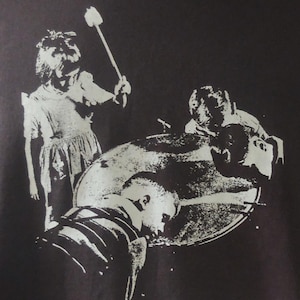 Könnte beinhalten: Dunkelgraues T-Shirt mit einer weißen Grafik, die Figuren um ein kreisförmiges Objekt zeigt, mit dem Text "Music à la Coque". Das T-Shirt hat kurze Ärmel und einen Rundhalsausschnitt.