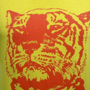 May include: A yellow t-shirt with a red tiger face graphic print.