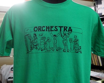 Op de afbeelding: Groen T-shirt met een zwarte cartoon-afbeelding van een orkest dat muziek maakt. De tekst "ORCHESTRA" is boven de afbeelding gedrukt.
