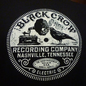 May include: Black and white graphic design of a vintage record label with the text "Black Crow Recording Company Nashville, Tennessee" and "The Lucky Thirteen Co. Made in the U.S.A. Nashville, Tennessee Electric".