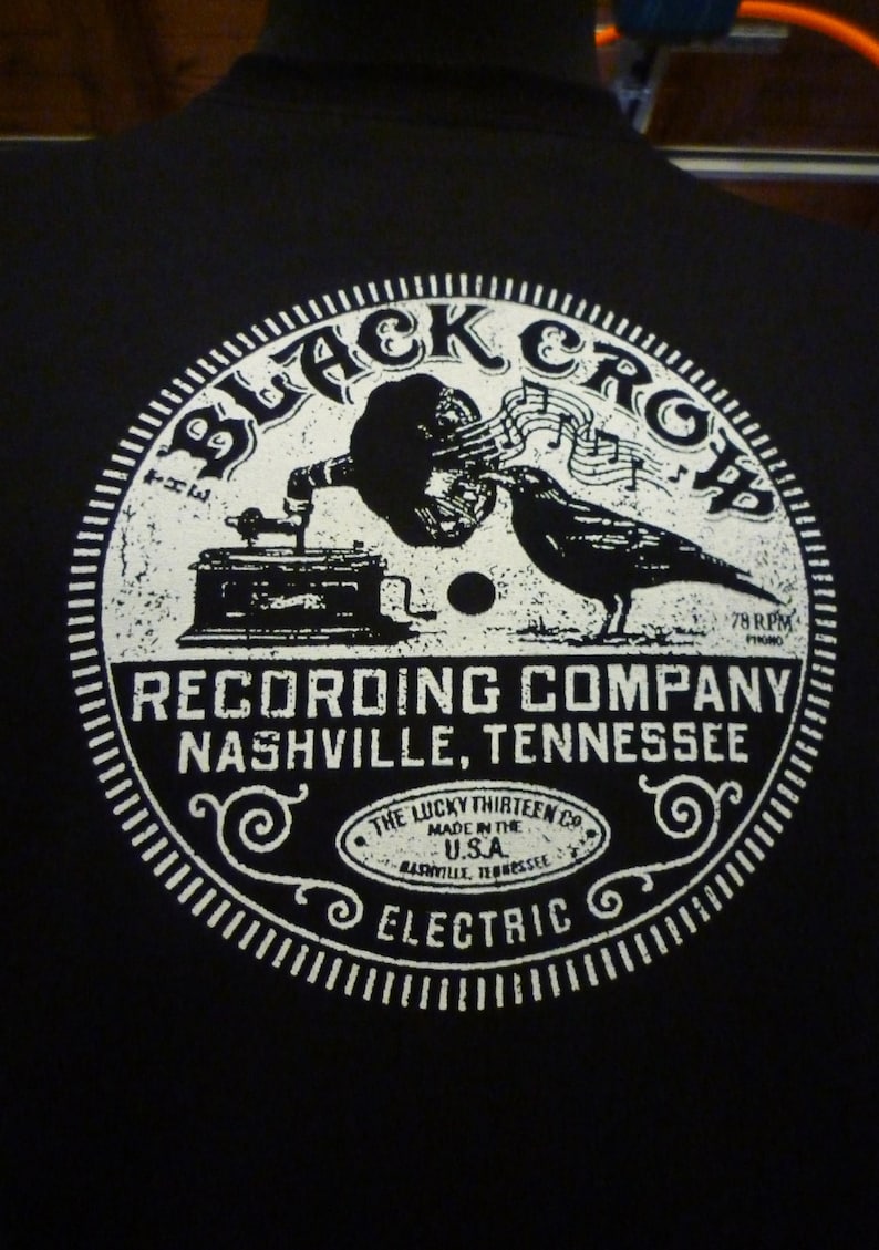 May include: Black and white graphic design of a vintage record label with the text "Black Crow Recording Company Nashville, Tennessee" and "The Lucky Thirteen Co. Made in the U.S.A. Nashville, Tennessee Electric".