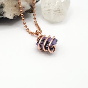 charoite wrapped with copper wire on a white background side view