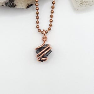 May include: A copper chain necklace with a black crystal pendant wrapped in copper wire.