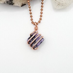 charoite wrapped with copper wire on a white background