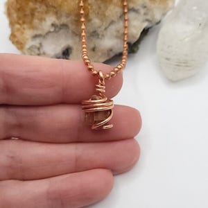 raw aragonite necklace in copper wire with a copper ball chain in hand