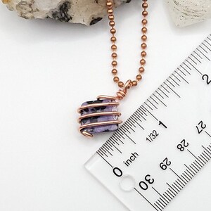 charoite wrapped with copper wire on a white background measurement about 1"