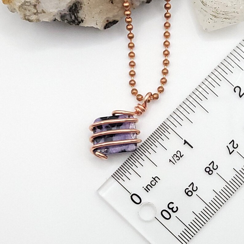 charoite wrapped with copper wire on a white background measurement about 1"