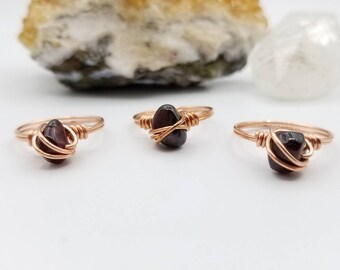 Op de afbeelding: Drie ringen van koperdraad met donkerrode edelsteen accenten.