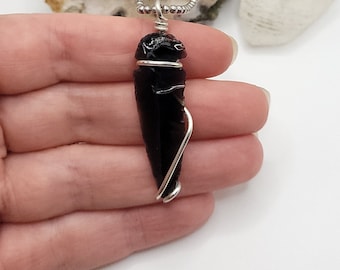 May include: Black obsidian arrowhead pendant wrapped in silver wire, hanging from a silver chain.