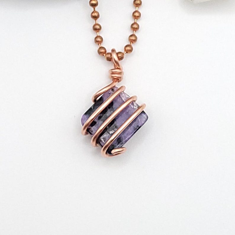 charoite wrapped with copper wire on a white background