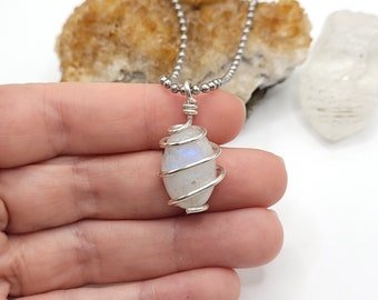 May include: A silver chain necklace with a white moonstone pendant wrapped in silver wire.