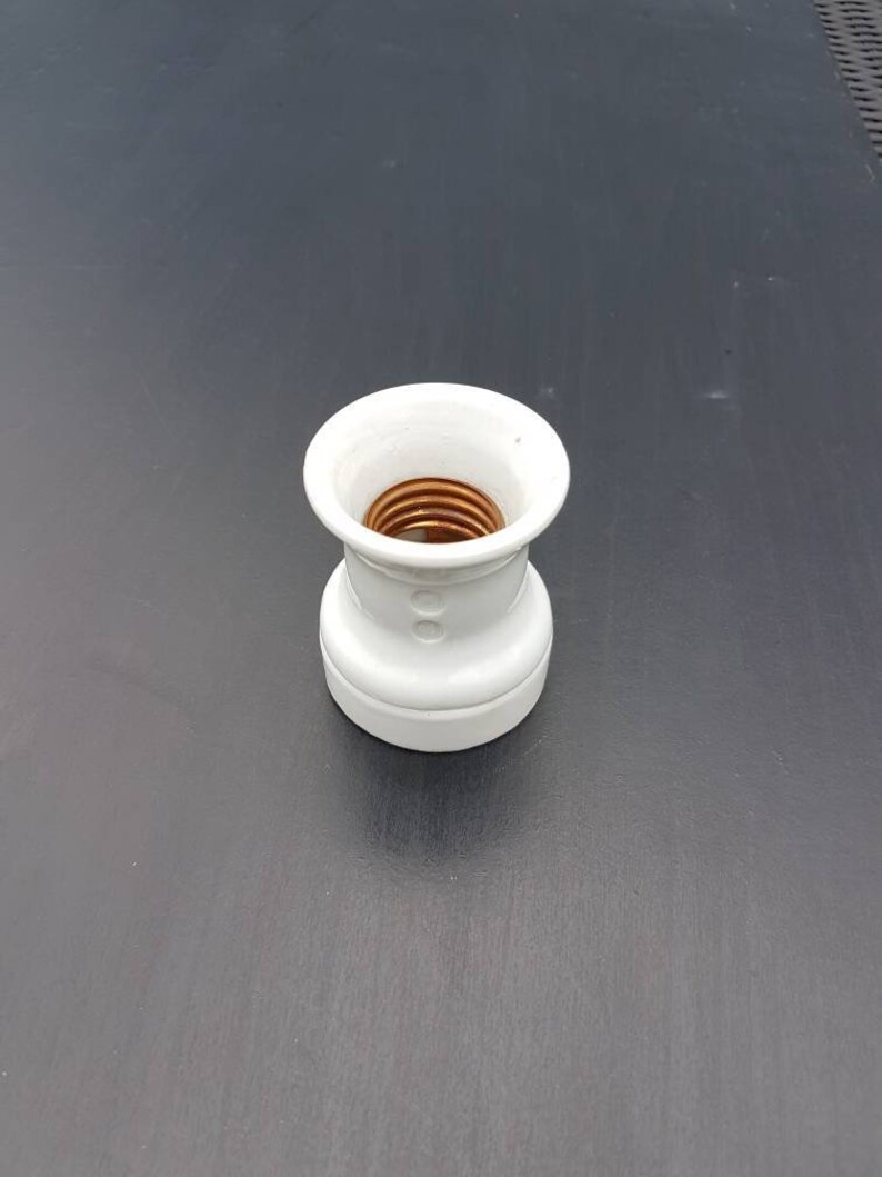 May include: White ceramic light bulb socket with a brass center.