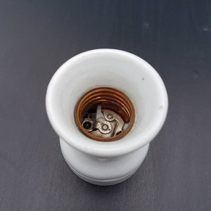 May include: White porcelain light bulb socket with copper and metal contacts.