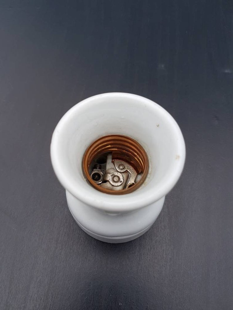 May include: White porcelain light bulb socket with copper and metal contacts.