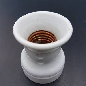 May include: White ceramic light bulb socket with a copper threaded center.