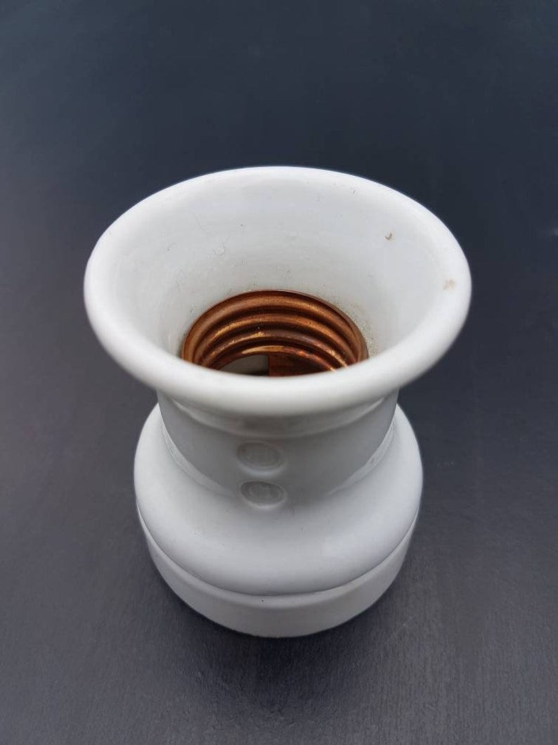 May include: White ceramic light bulb socket with a copper threaded center.