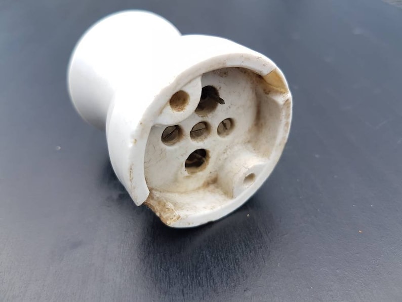 May include: White ceramic electrical outlet with four holes for wiring. The outlet is designed for use with a light bulb.