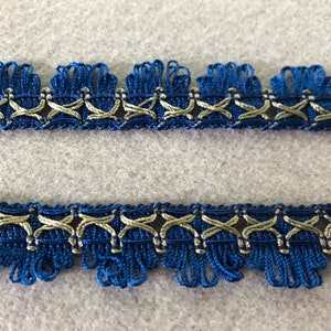 May include: Blue and gold trim with a fringe edge. The trim has a woven design with a repeating pattern.