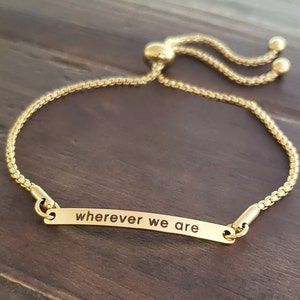 May include: Gold adjustable bracelet with a small rectangular tag that reads "wherever we are".