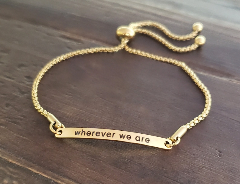 K&ouml;nnte beinhalten: Goldenes verstellbares Armband mit einem kleinen rechteckigen Anh&auml;nger mit der Aufschrift "wherever we are".
