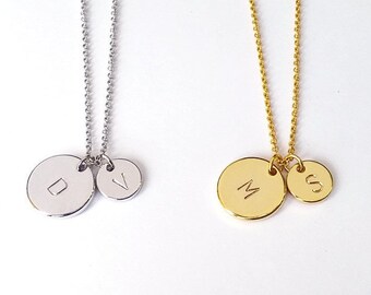 May include: Two silver necklaces with round pendants. The pendants have the letters "D" and "V" engraved on them. Two gold necklaces with round pendants. The pendants have the letters "M" and "S" engraved on them.