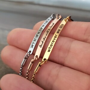 K&ouml;nnte beinhalten: Drei Armb&auml;nder aus Silber, Gold und Ros&eacute;gold mit graviertem Text. Das silberne Armband tr&auml;gt die Aufschrift "34.1' 57.18' N, 118.19' 11.92' W". Das goldene Armband tr&auml;gt die Aufschrift "And she will be loved". Das ros&eacute;goldene Armband tr&auml;gt die Aufschrift "wherever we are".