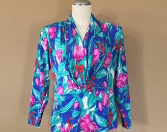 Puede incluir: Una blusa de estampado floral azul, verde, rosa y rojo con cuello en V y mangas largas.