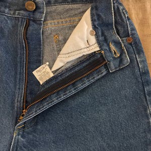 May include: A pair of blue denim jeans with a zip fly and a button fastening. The jeans have a light wash and are made of a soft, comfortable fabric.