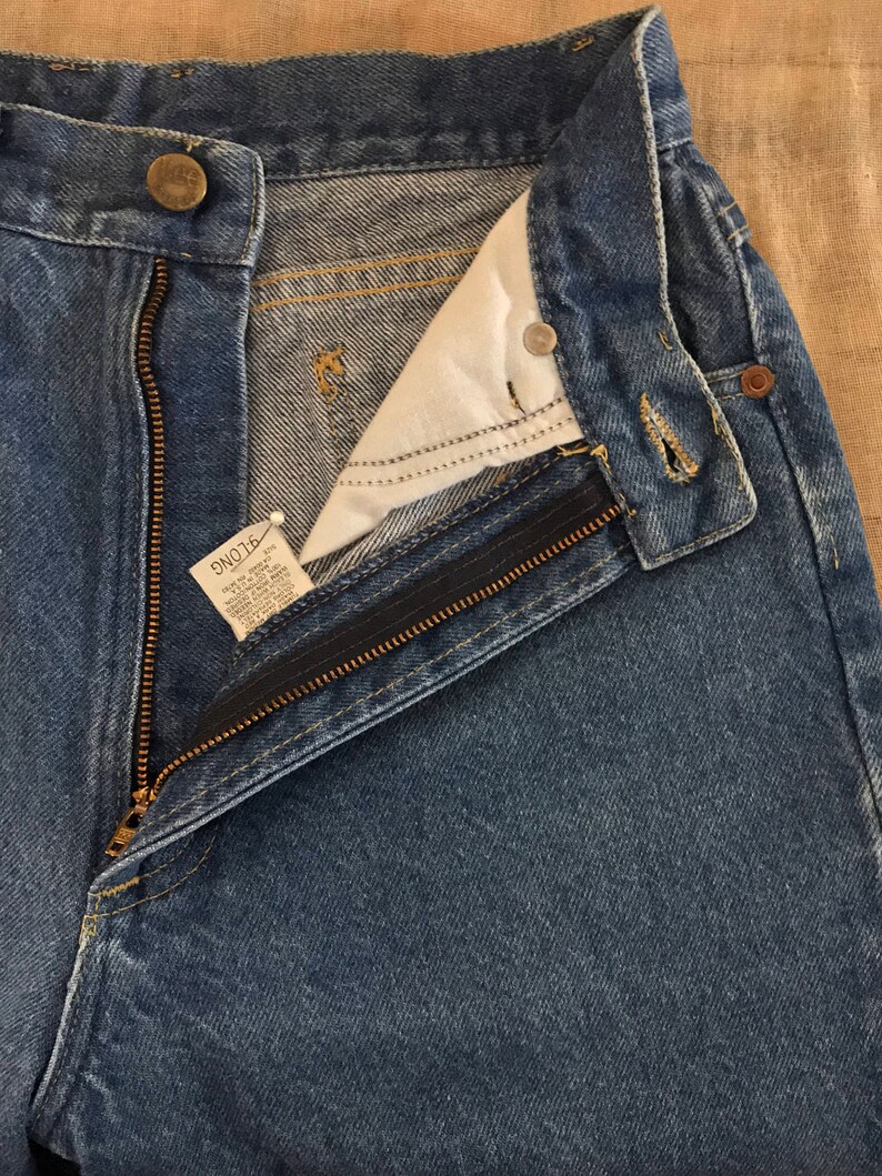 May include: A pair of blue denim jeans with a zip fly and a button fastening. The jeans have a light wash and are made of a soft, comfortable fabric.