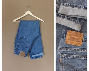 May include: A pair of blue denim jeans with a brown leather patch that says "Levi Strauss & Co.  Original  Riveted  Quality  Clothing  1881  501  M".