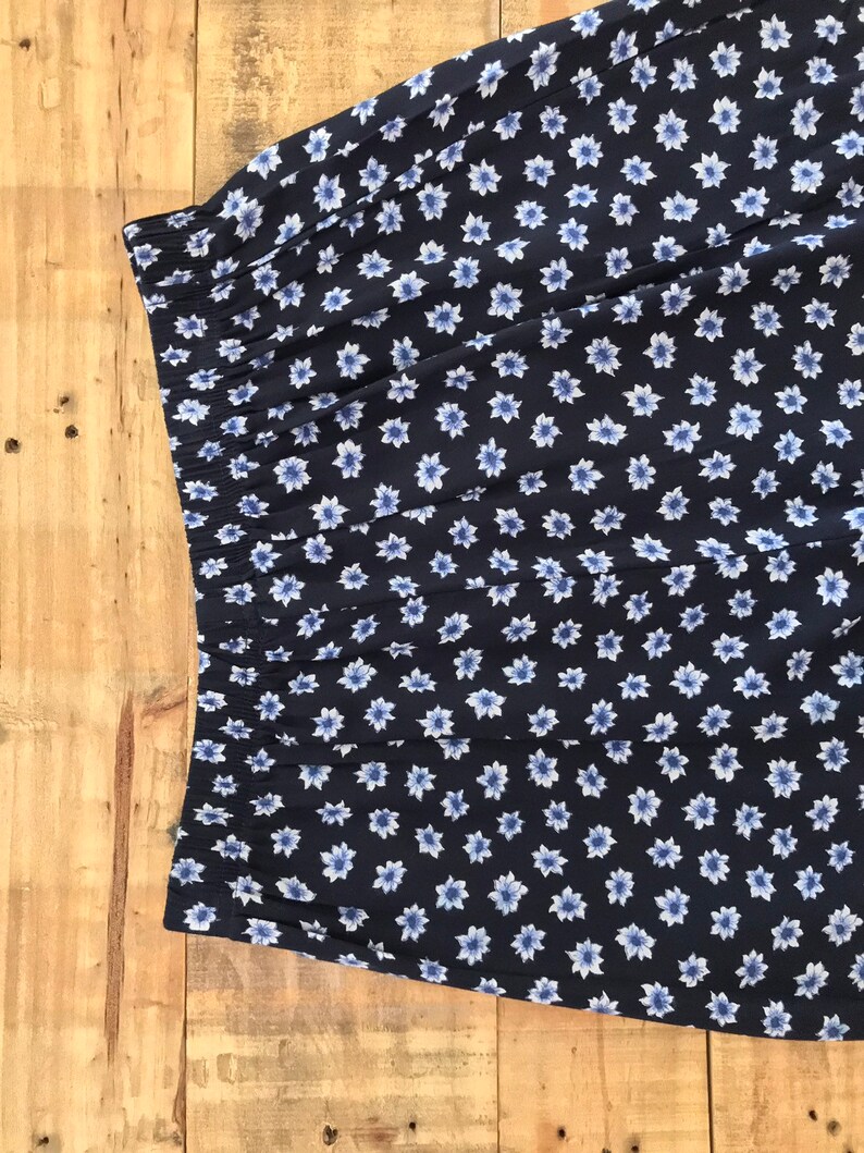 Puede incluir: Una tela azul marino con un estampado floral blanco. La tela tiene una cintura el&aacute;stica fruncida.